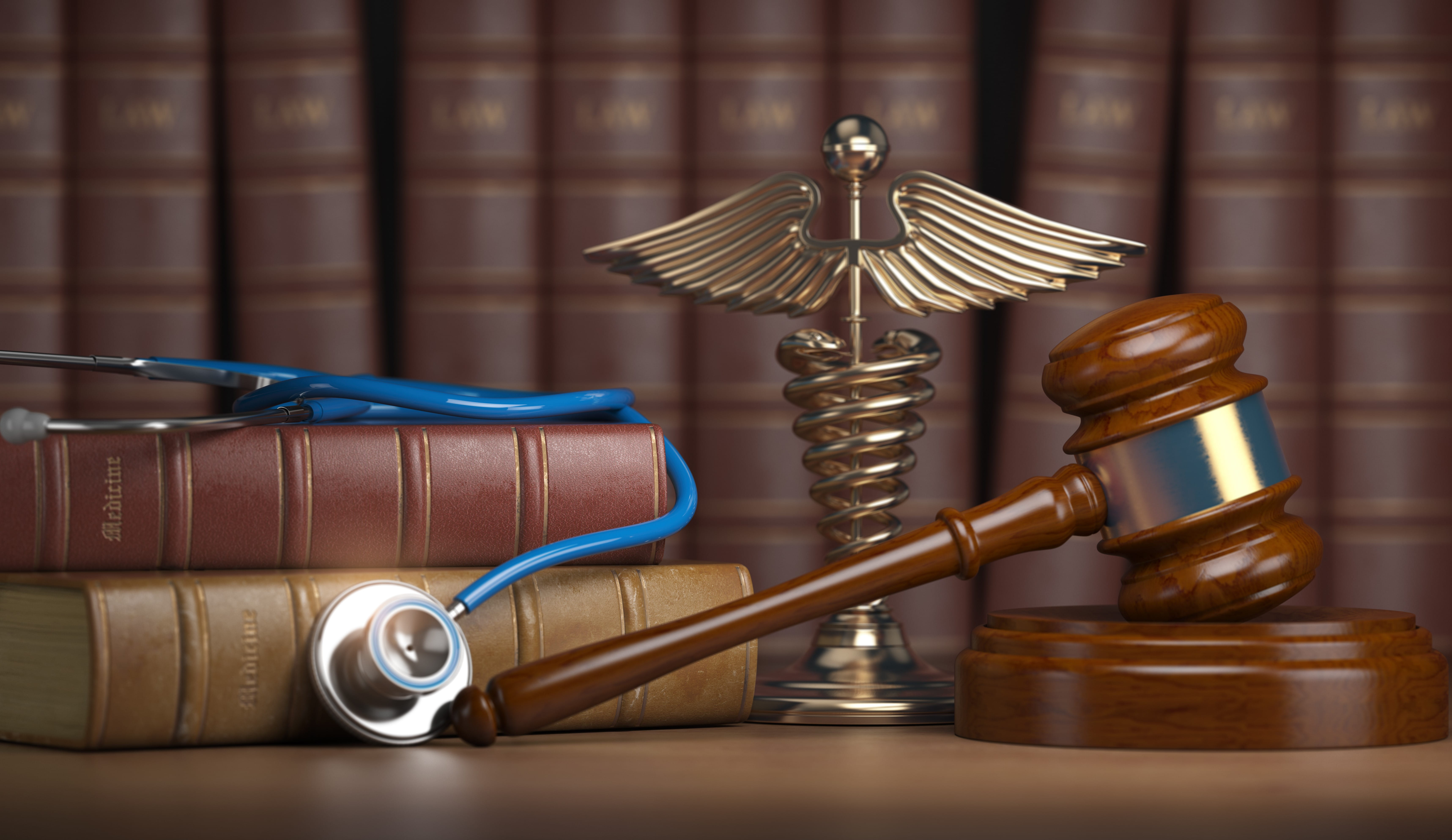 Gavel, stethoscope, medical symbol statue and leather-bound books