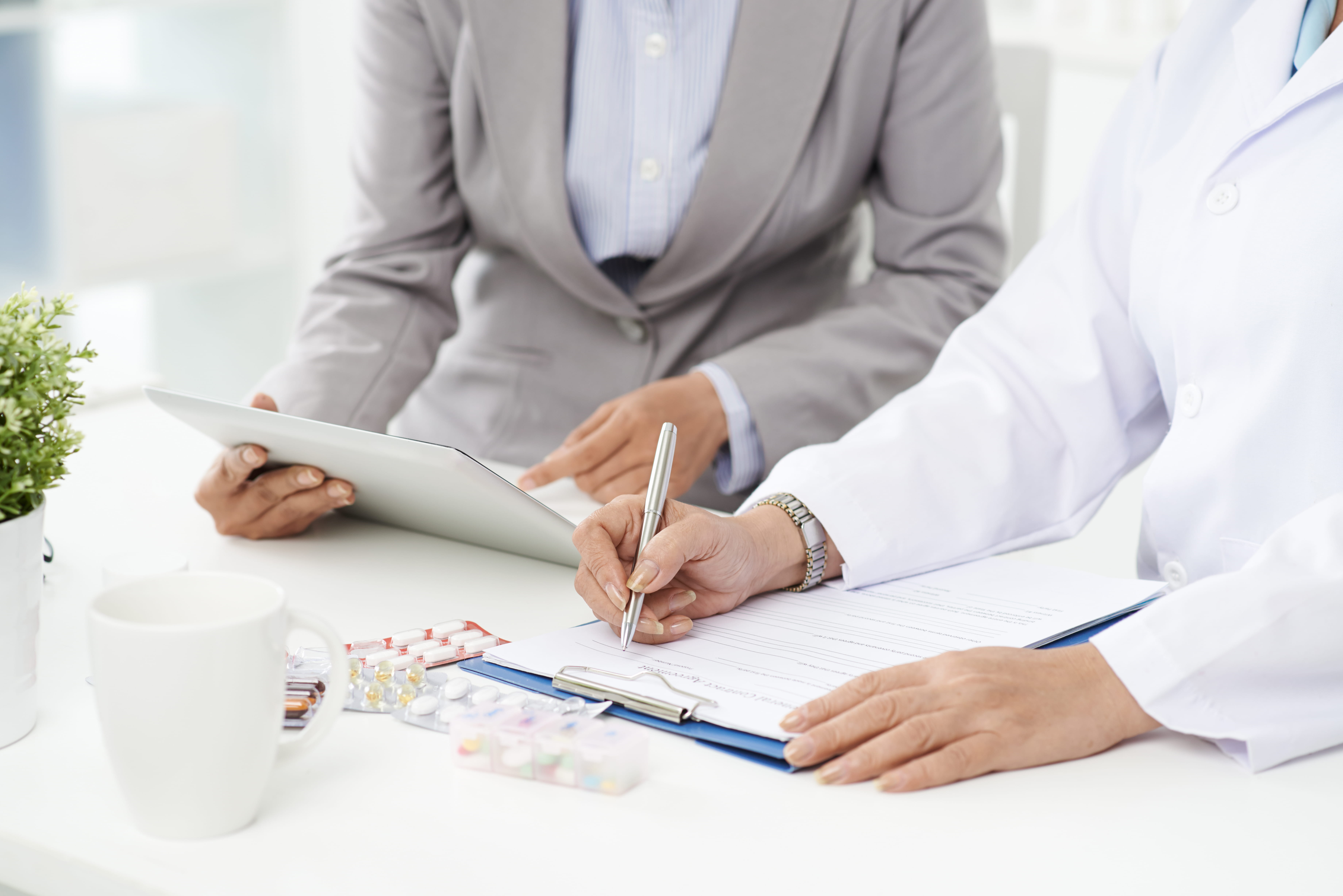 Doctor and hospital employee going over paperwork and reviewing on a tablet